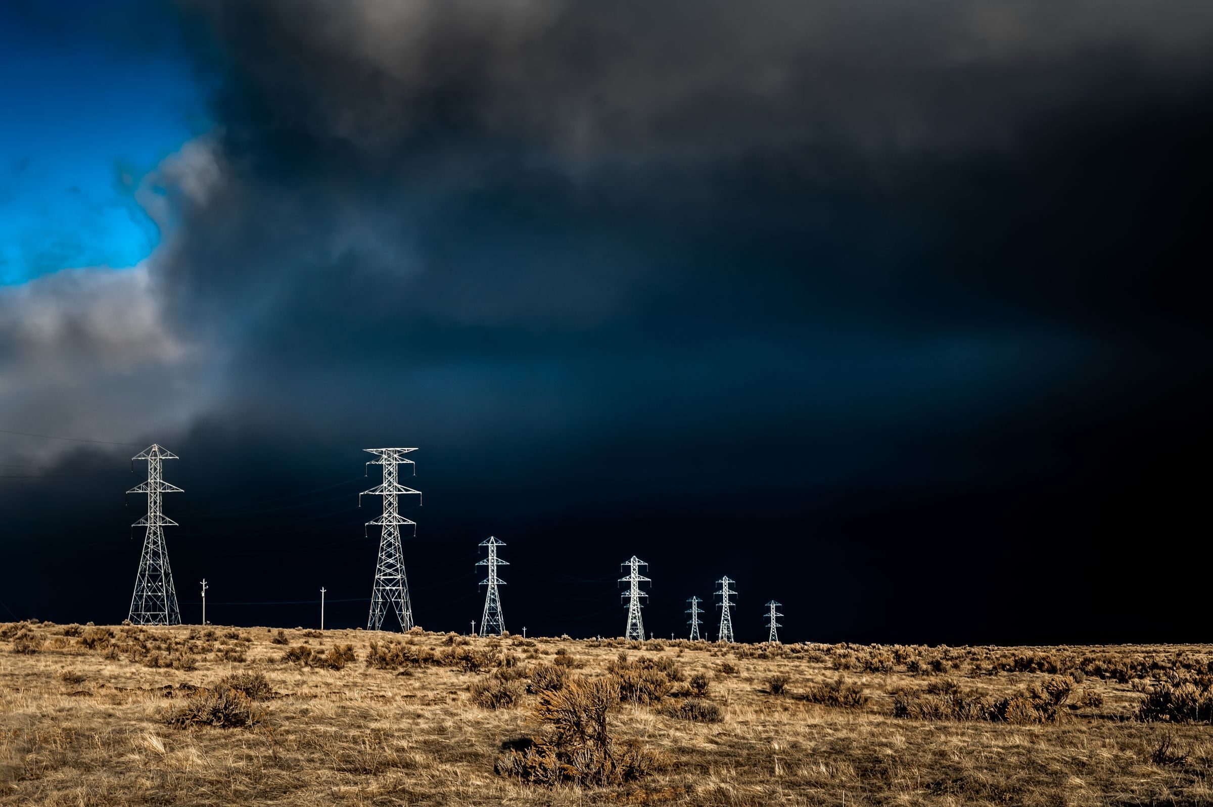 Hochspannungsmasten vor dunklem Himmel